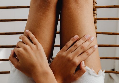 Close-up of a person's hands resting peacefully on their knees.